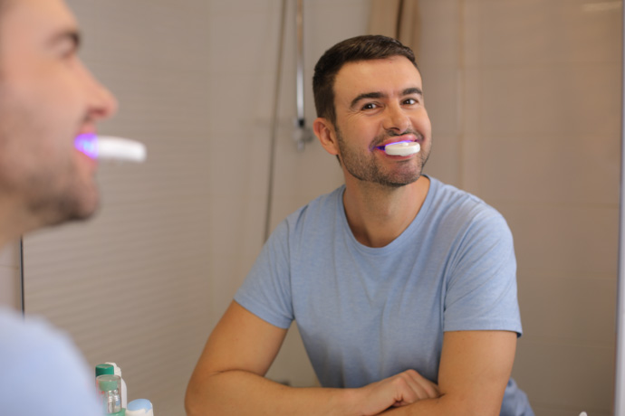 Chico enseñando cómo blanquear los dientes en casa.