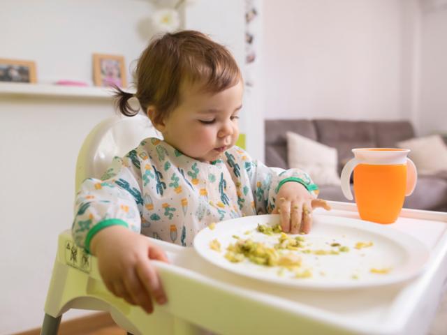 Niña pequeña comiendo en su silla alta