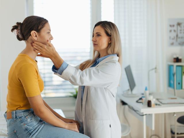 Médico explorando un bulto en el cuello de su paciente