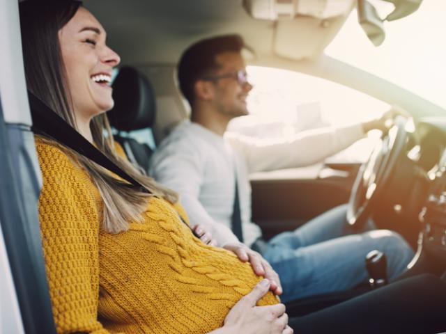 Mujer embarazada en un coche con su pareja.