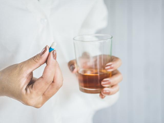 Mujer tomando antibióticos con alcohol.