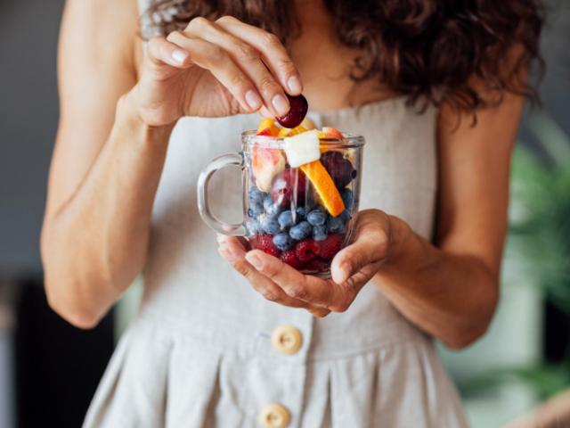 Mujer tomando frutas recomendadas para diabéticos.