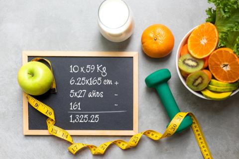 Elementos representativos de una vida saludable: manzana, cítricos, cinta métrica, pesa liviana