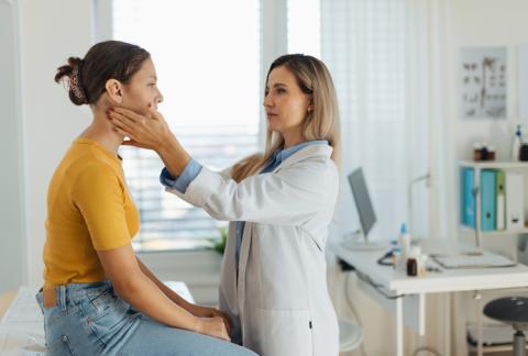 Médico explorando un bulto en el cuello de su paciente